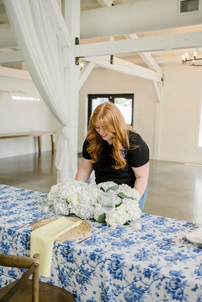 wedding florist placing a floral table design at a wedding venue. 