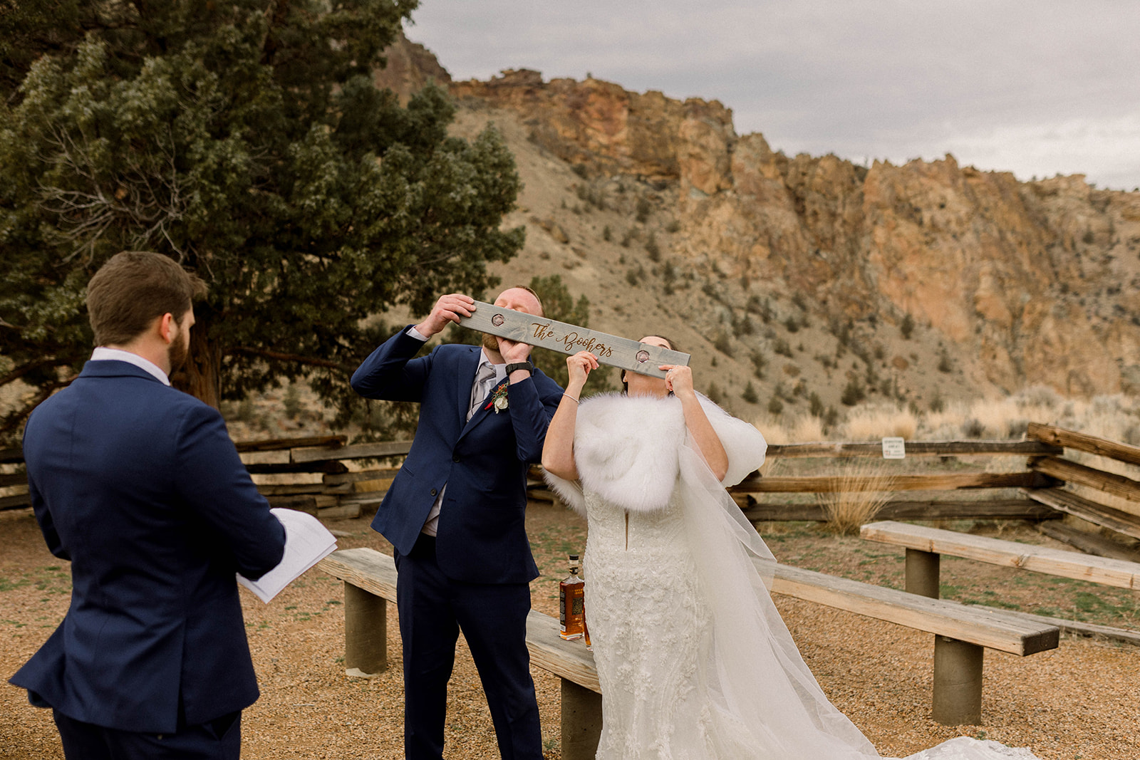 couple in a mountain setting doing a shot-ski shot during their wedding ceremony